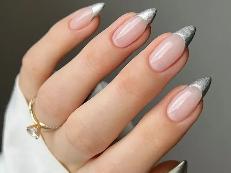 Chrome French Tip Nails 2026: 32 Designs and What to Tell Your Nail Tech 6 Silver chrome French tips with small crystals on two accent nails